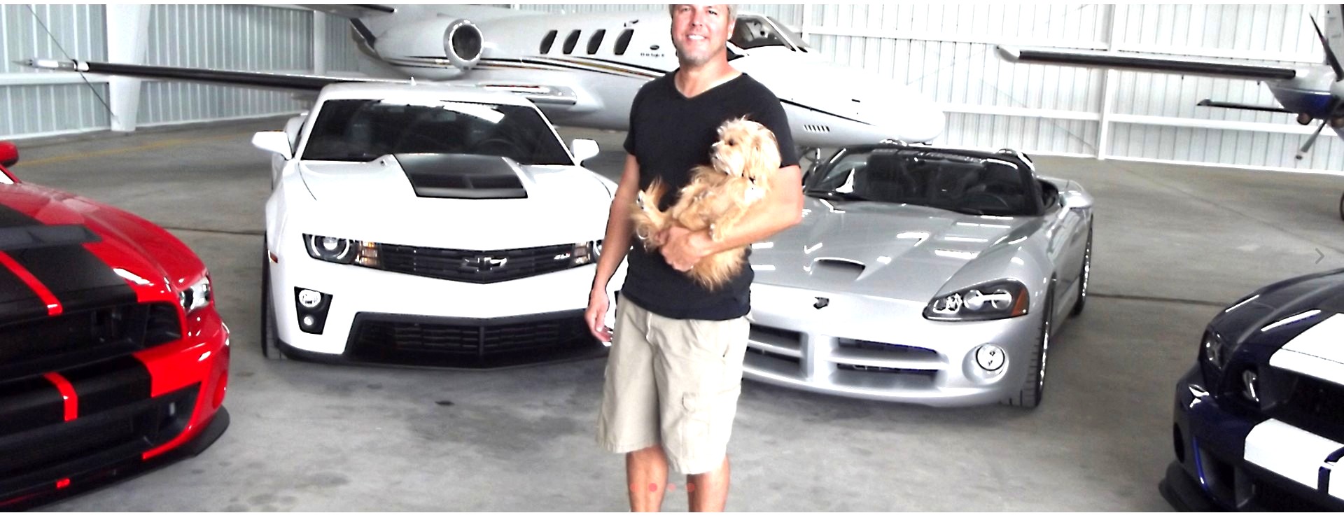 Chris with his cars and jet in a hangar