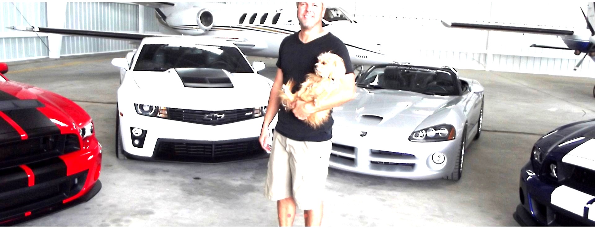 Chris with his cars and jet in a hangar